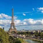 Paris skyline featuring Eiffel Tower, Seine River, and mix of traditional and modern buildings.
