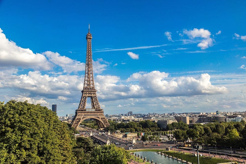 Paris skyline featuring Eiffel Tower, Seine River, and mix of traditional and modern buildings.