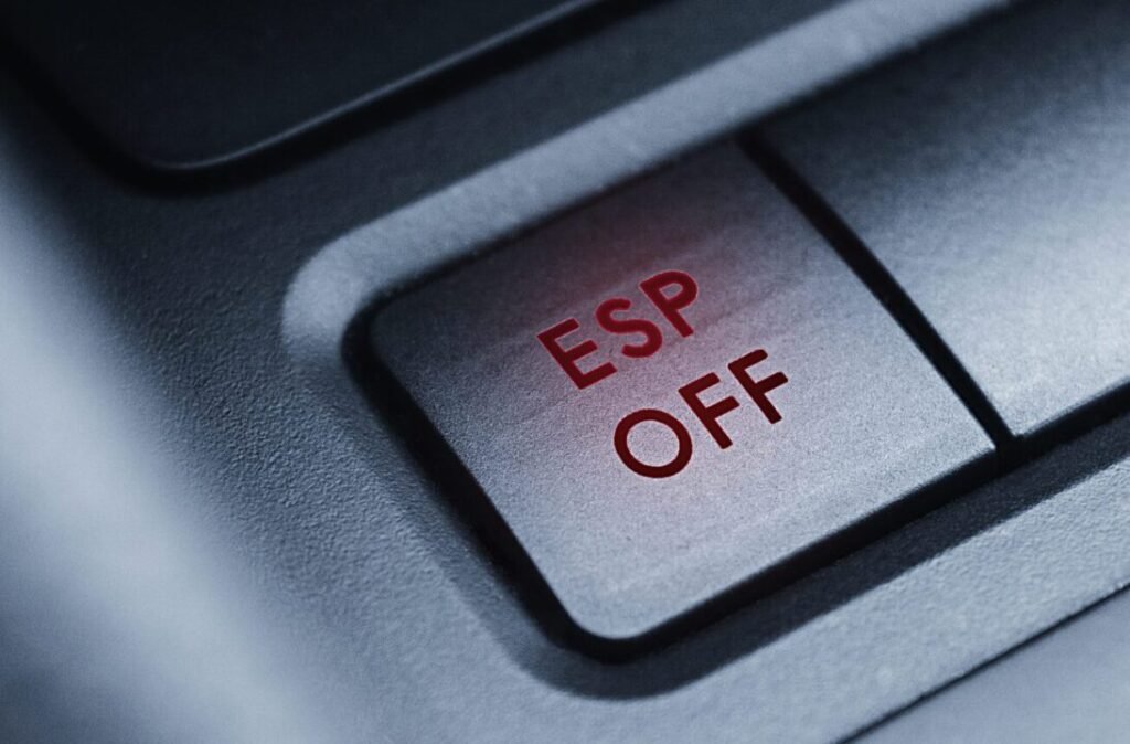 Close-up of a car's ESP OFF button illuminated in red on a black background.