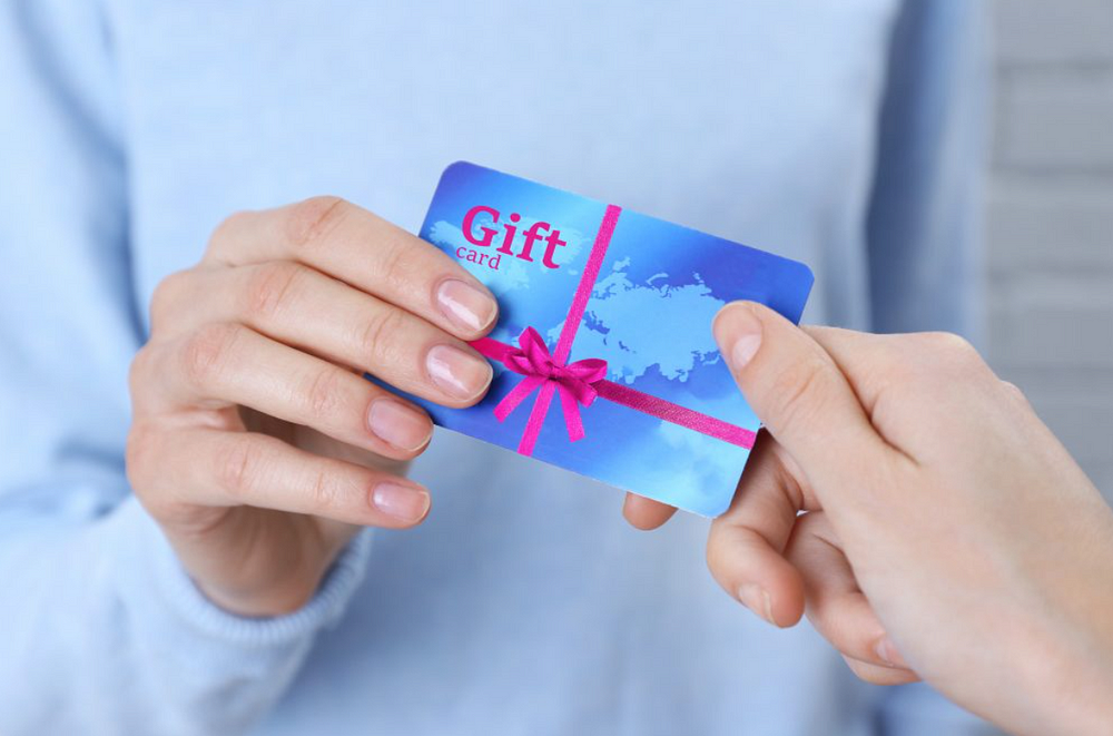 Hands exchanging blue gift card symbolizing gesture of giving and receiving in a professional setting.