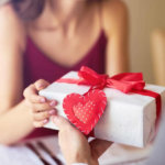 Intimate gift exchange with red ribbon and heart decoration.
