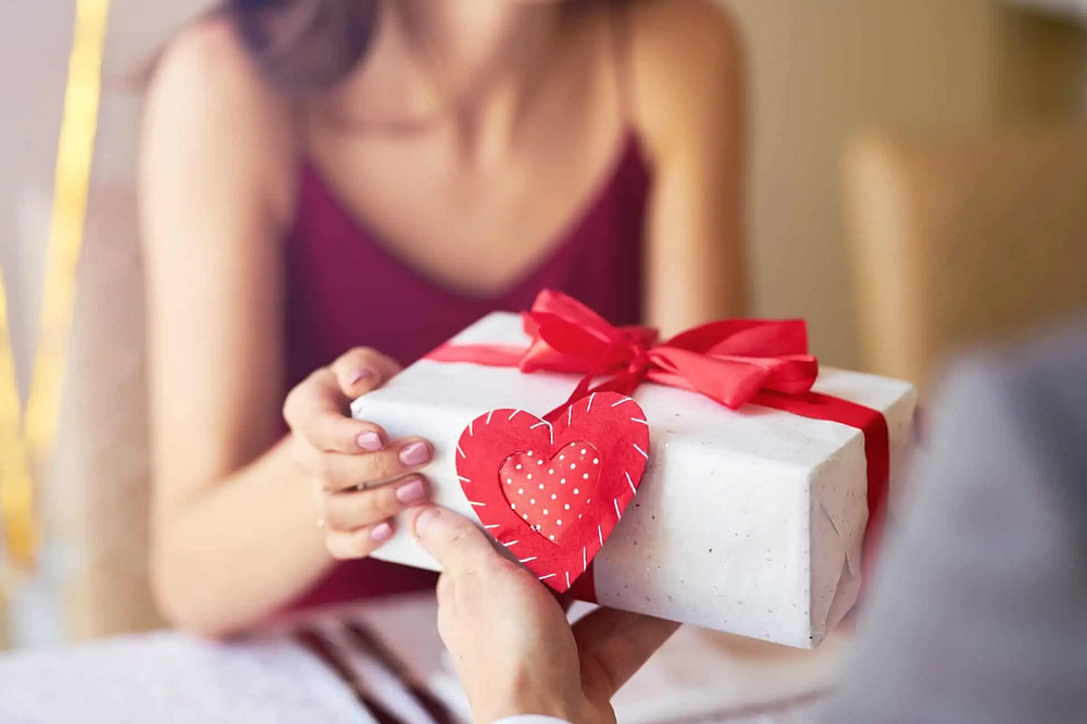 Intimate gift exchange with red ribbon and heart decoration.