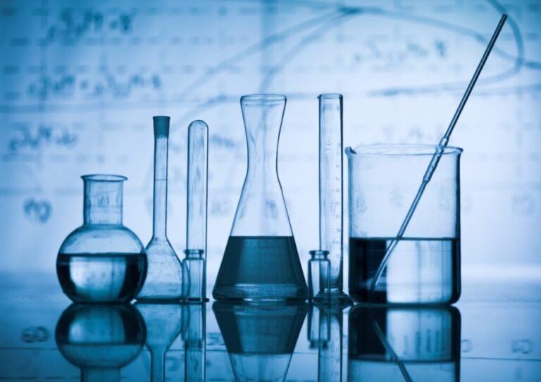 Glass laboratory equipment on reflective surface with scientific diagrams, showcasing precision and experimentation.