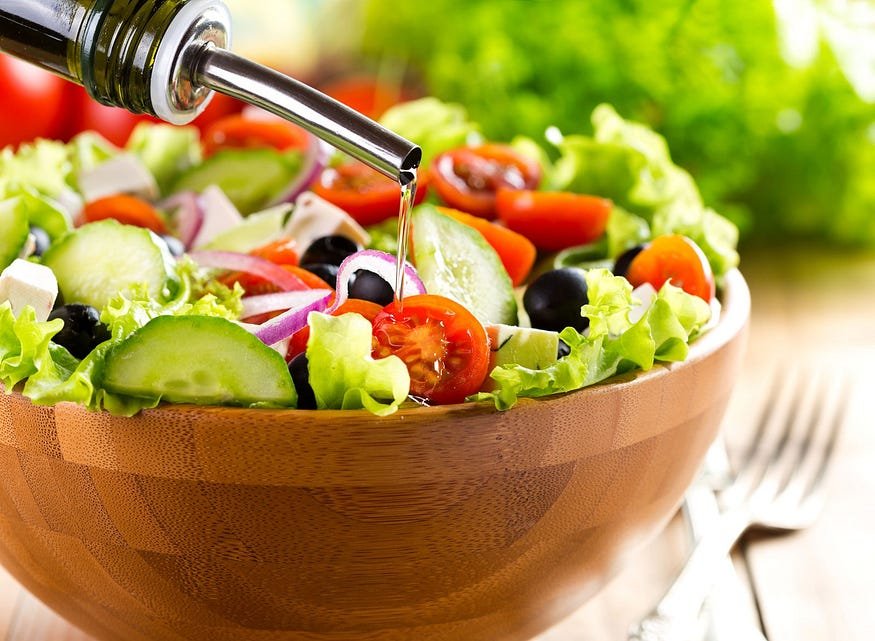 Fresh Greek salad with colorful veggies and dressing pour, ready to eat.