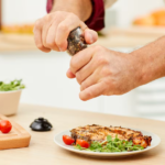 Grilled chicken with fresh veggies, cherry tomatoes, and olive oil on kitchen counter.