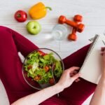 Balanced health and fitness setup with salad, fruits, dumbbells, and water for wellness.