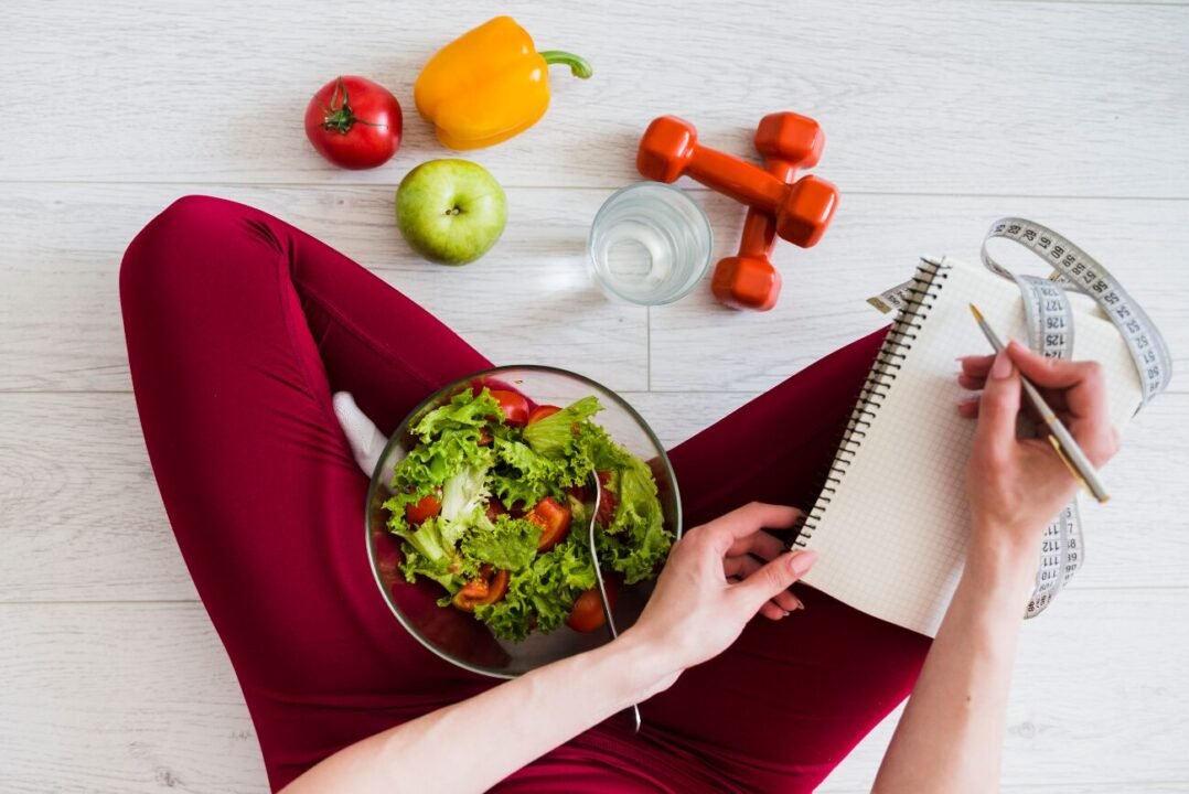 Balanced health and fitness setup with salad, fruits, dumbbells, and water for wellness.