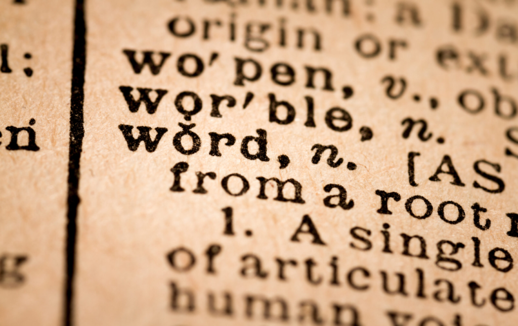 Close-up of a dictionary page highlighting the word "word" with its definition and phonetic transcription, slightly faded and yellowed with age.