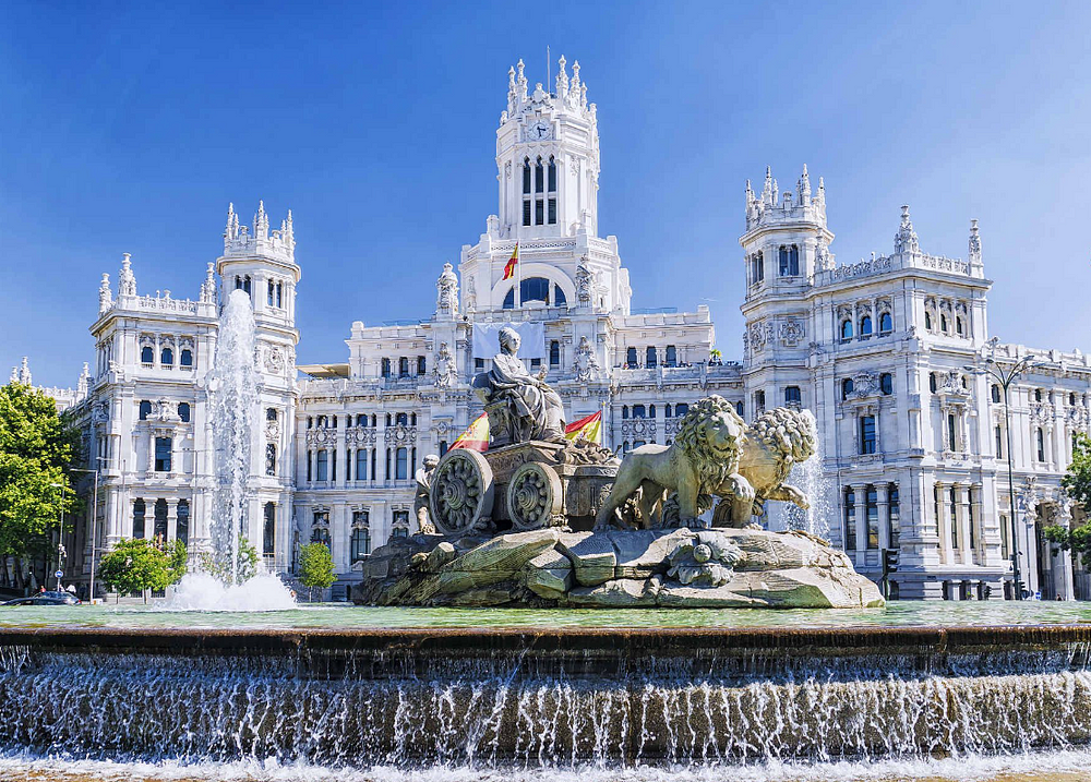 Historical landmark in Madrid: Majestic palace with lion fountain under sunny sky.