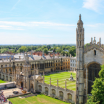 Historic Gothic university complex with towers, spires, courtyard, and cityscape view in old European city.