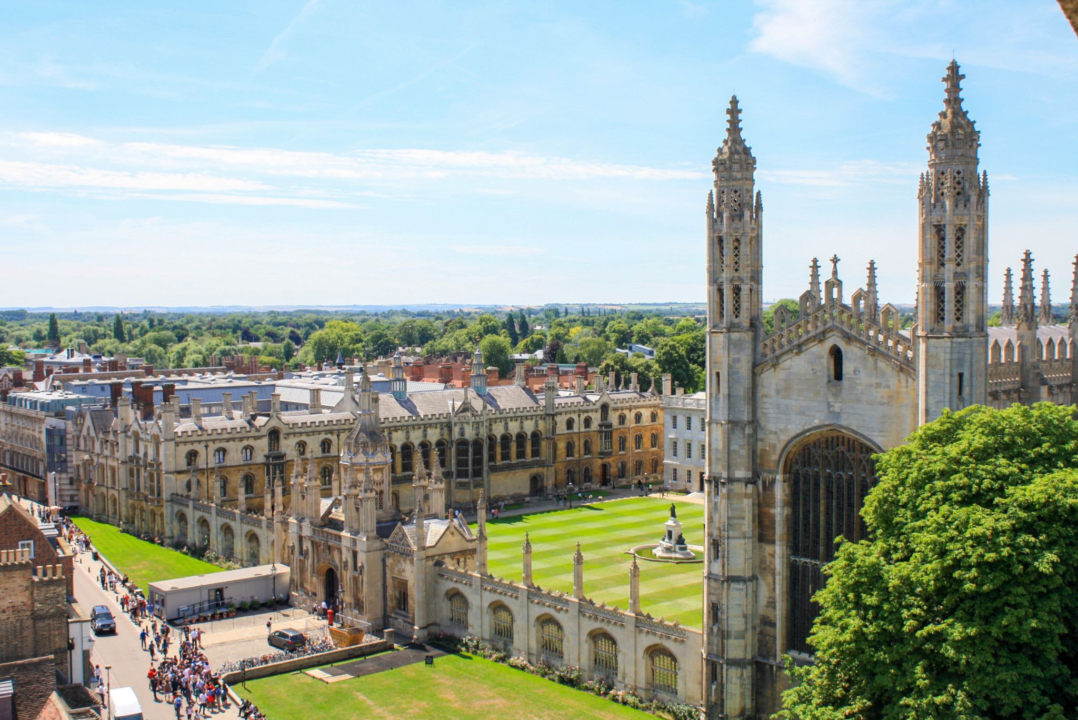 Historic Gothic university complex with towers, spires, courtyard, and cityscape view in old European city.