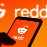 Hand holding smartphone with glowing Reddit logo, symbolizing digital connectivity and social interaction.