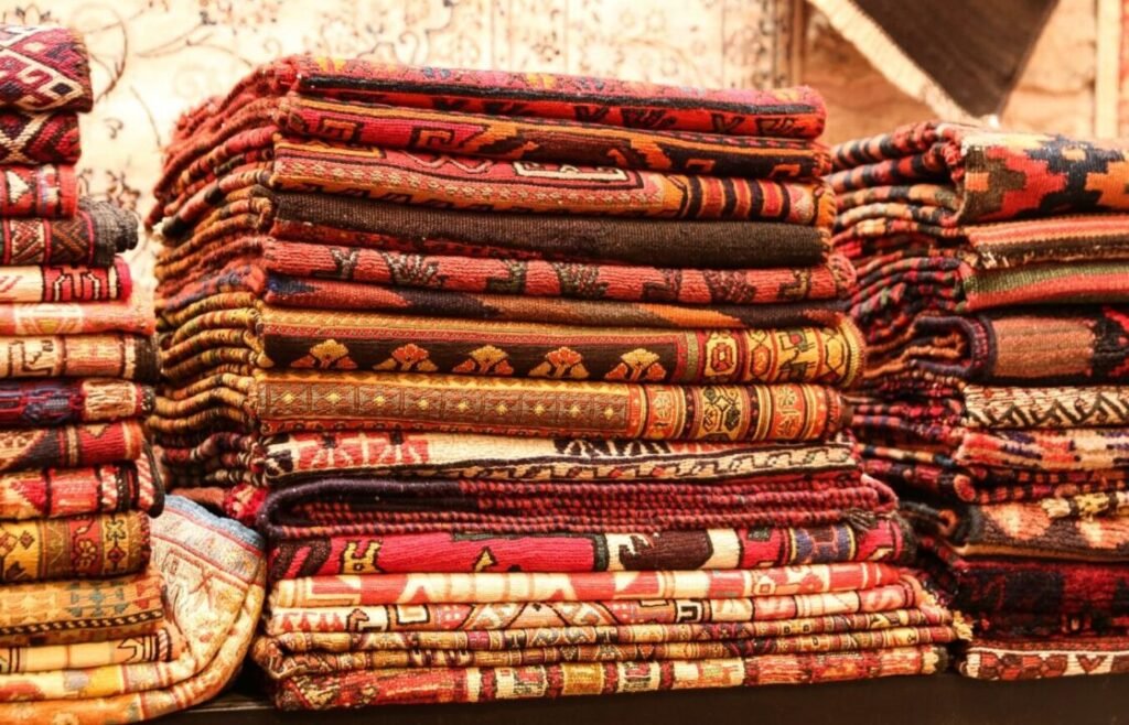 Stacks of colorful, intricately designed handwoven rugs.