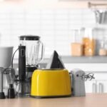 Modern kitchen countertop with coffee maker, blender, and yellow toaster in a contemporary setting.