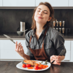 Happy chef enjoying aroma of grilled chicken in stylish modern kitchen setting.