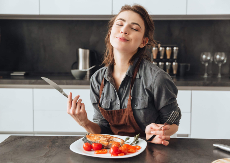 Happy chef enjoying aroma of grilled chicken in stylish modern kitchen setting.