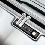 Close-up view of silver luggage combination lock with keyhole for secure travel.