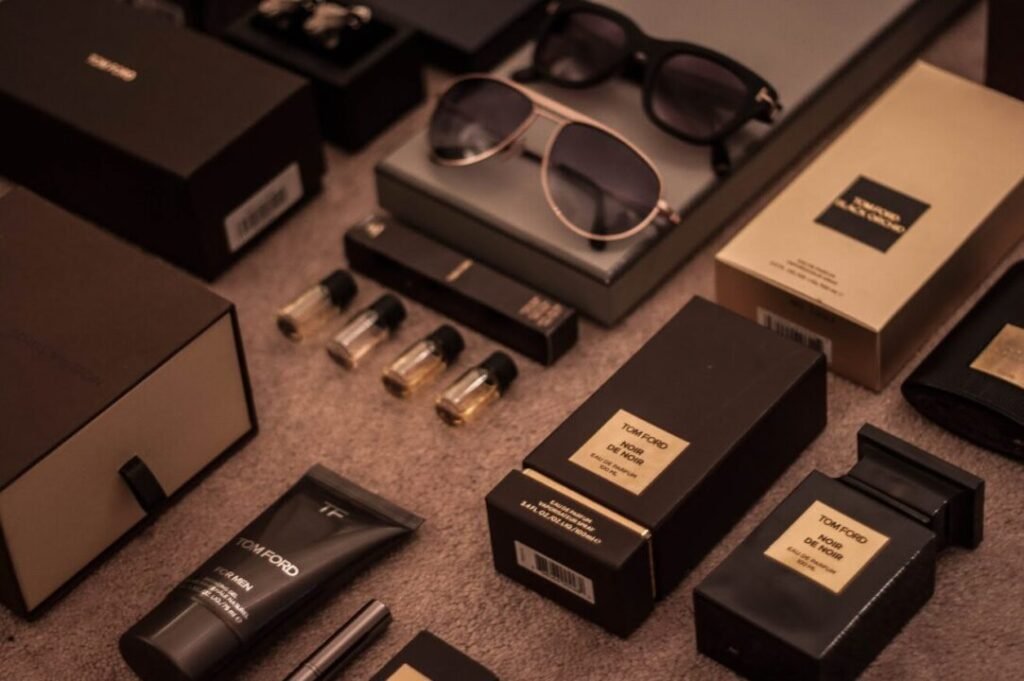 Assortment of luxury fashion products including sunglasses, perfume bottles, and cosmetic items from Tom Ford, displayed with their packaging on a carpeted floor.