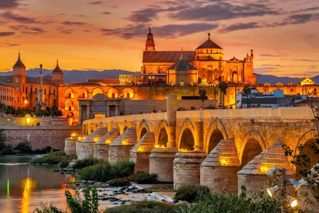Historic Roman bridge and cathedral in Córdoba, Spain at twilight.