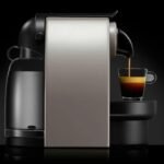 Modern espresso machine brewing rich espresso into glass cup on black background.