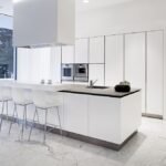 Modern white kitchen with marble island, sleek design, natural light, and minimalist decor.