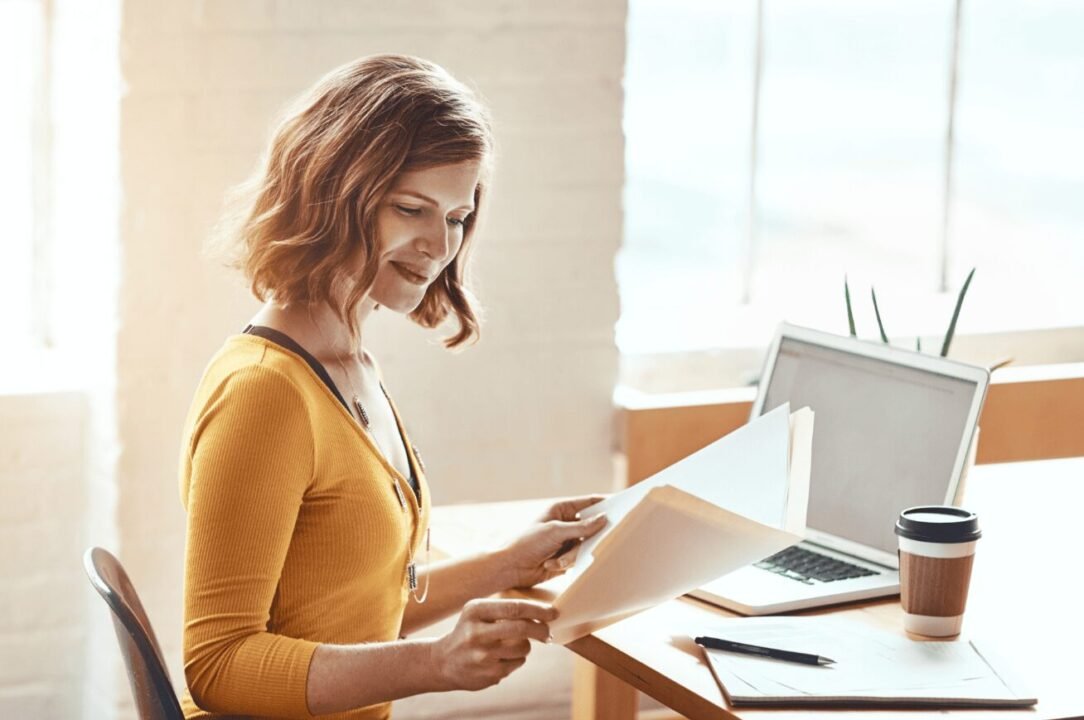 Cozy workspace with woman in mustard top, laptop, and coffee cup for productivity.