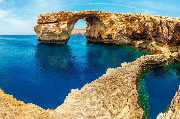 Breathtaking limestone arch over crystal blue sea: majestic coastal beauty.
