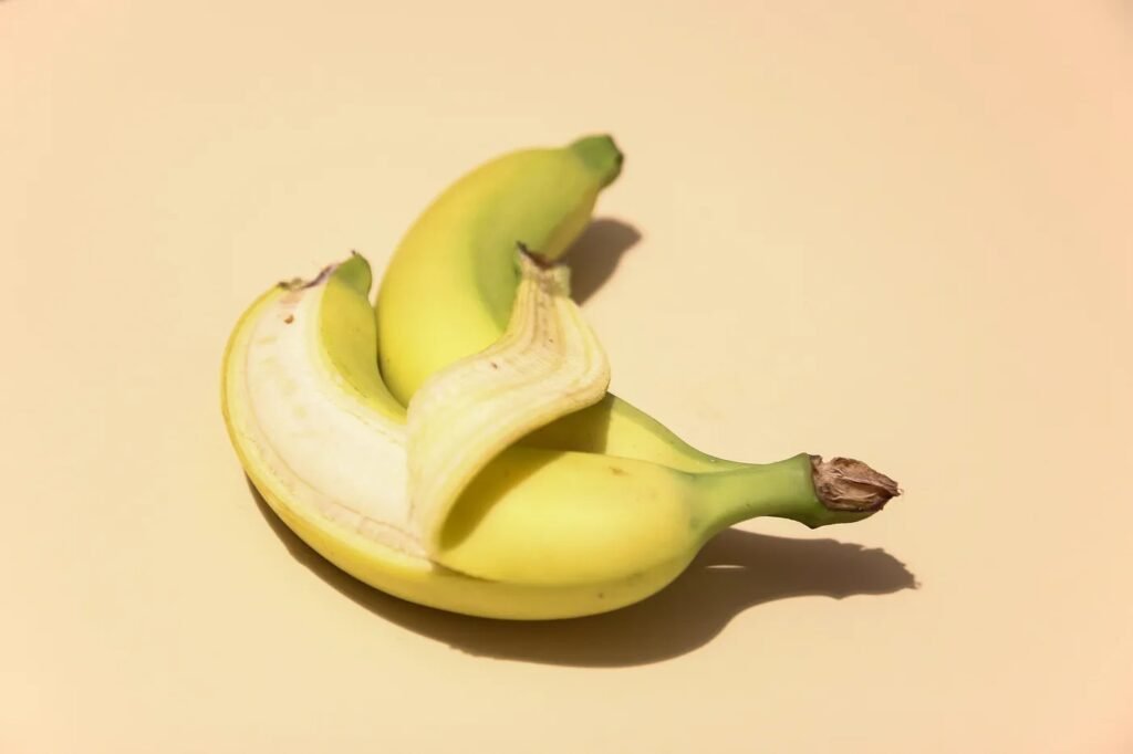 A partially peeled banana on a beige background.