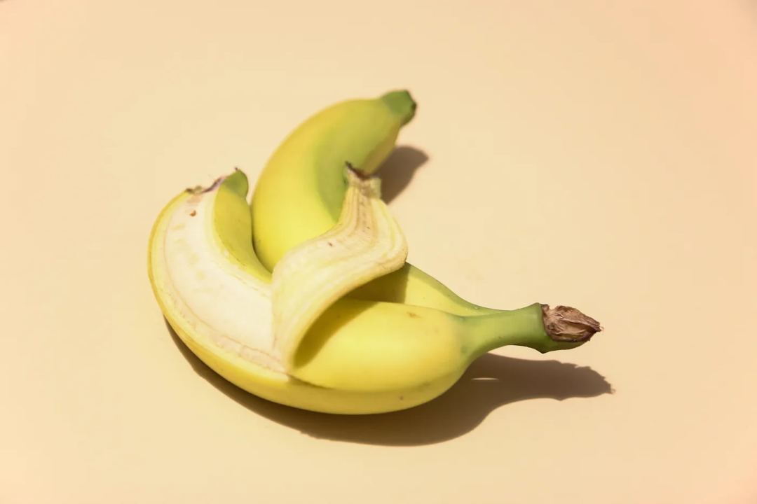 A partially peeled banana on a beige background.