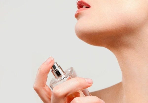 Elegant woman applying perfume for special occasion, holding bottle with spray nozzle.