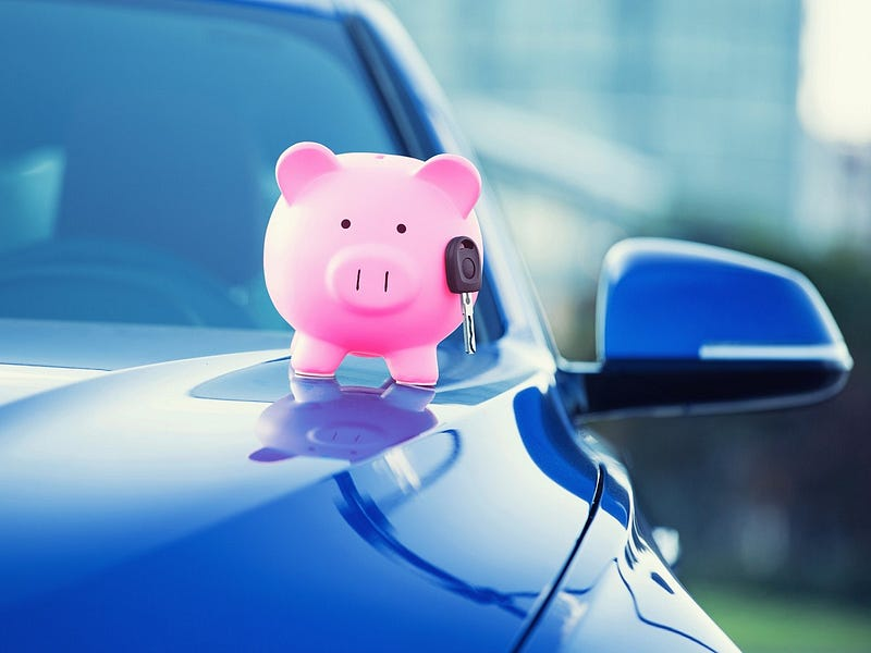 A pink piggy bank with a car key inserted into the slot, sitting on the hood of a blue car with blurred background.