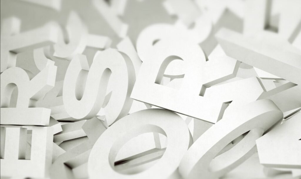 A pile of random cut-out paper letters in shades of white and gray with a shallow depth of field.