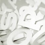 Scattered white letters in various fonts creating a chaotic composition with shadows.