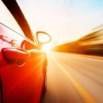 Red car racing at sunset, blurred motion with high speed.