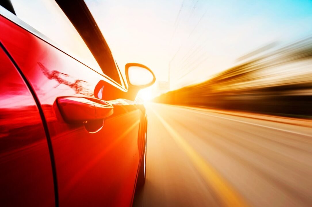 Red car racing at sunset, blurred motion with high speed.