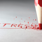 Red pencil breaks, spelling STRESS on white surface - symbolizing reaching a breaking point.