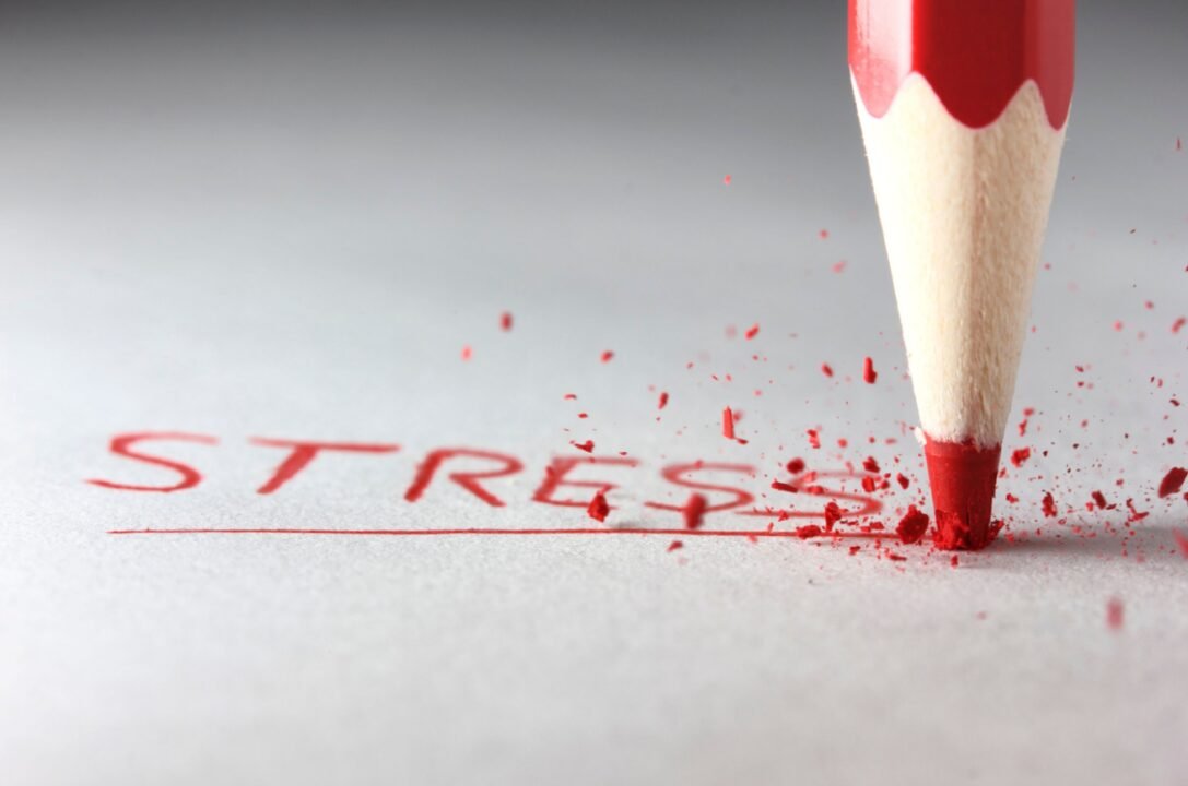 Red pencil breaks, spelling STRESS on white surface - symbolizing reaching a breaking point.