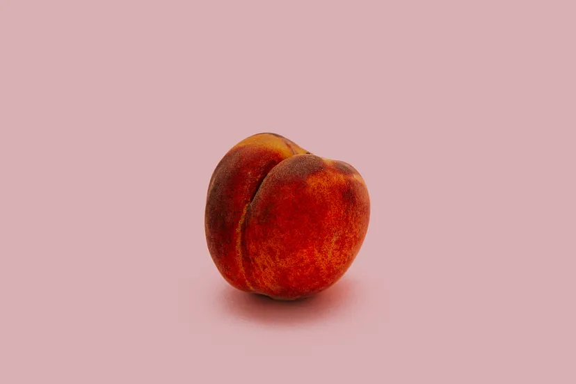 Ripe peach on pink backdrop - minimalist fruit photo.