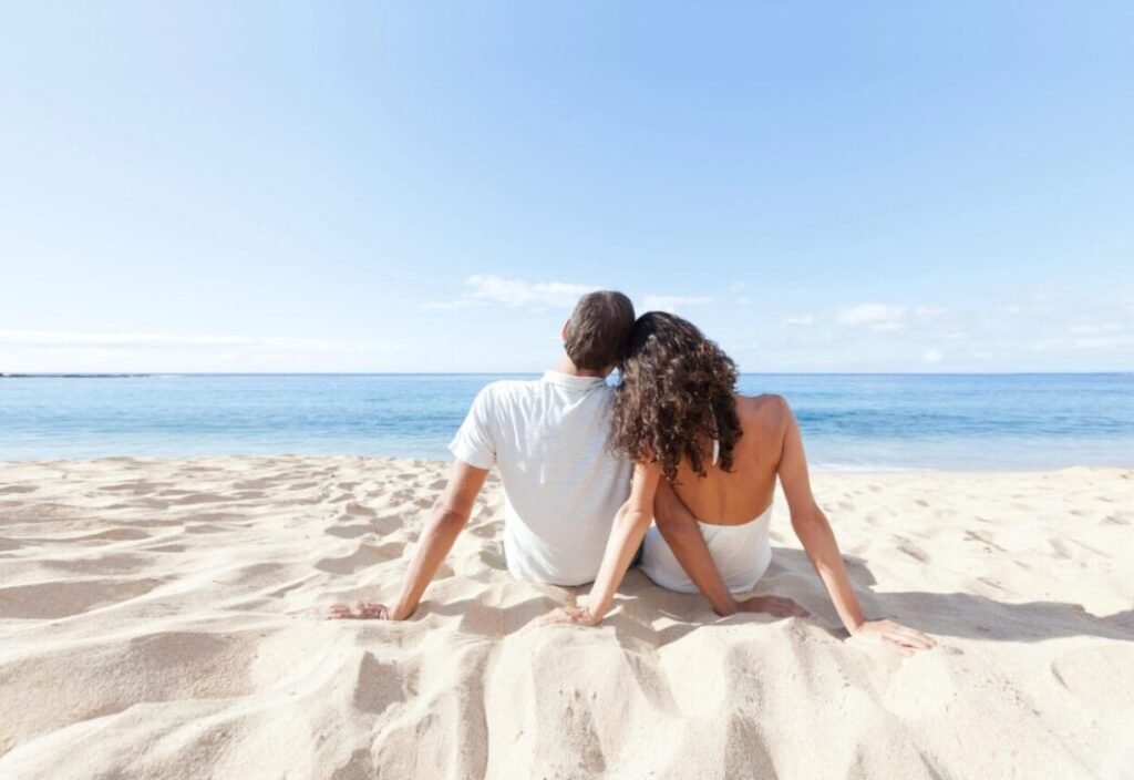 Romantic couple enjoying tranquil beach view under clear blue sky.