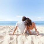 Romantic couple enjoying tranquil beach view under clear blue sky.