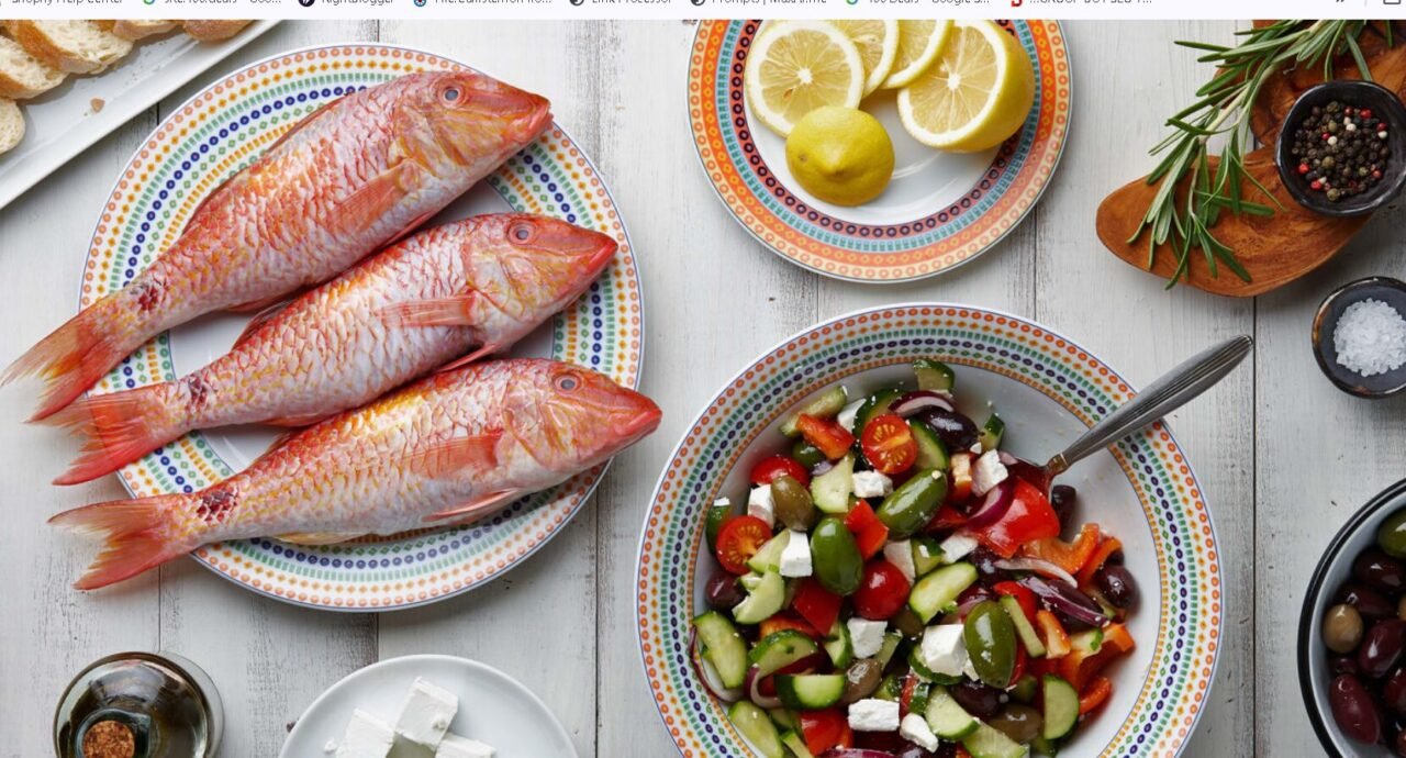 Fresh seafood feast with Greek salad, condiments, and seasonings on rustic wooden table.