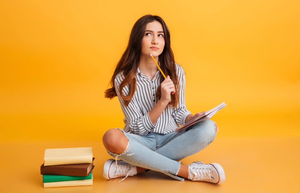 Contemplative woman with books on vibrant orange background.