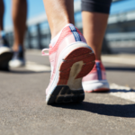 Two people walking in athletic shoes on a sunny day outdoors.