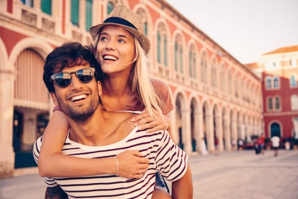 Couple embracing joyfully in a sunny European city street.