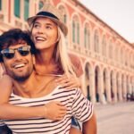 Couple embracing joyfully in a sunny European city street.