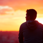 Tranquil moment: person contemplating vibrant sunset sky.