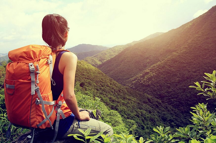 Woman in nature: Serene moment amidst lush green mountains, looking out in tranquility.