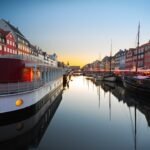 Tranquil evening by colorful canal with boats, vibrant buildings, and cozy ambiance in Copenhagen.