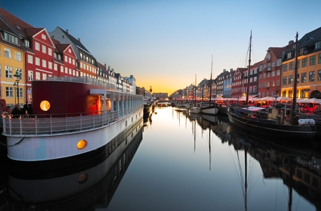 Tranquil evening by colorful canal with boats, vibrant buildings, and cozy ambiance in Copenhagen.