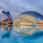 Serene modern architecture reflected on calm waters under twilight sky.